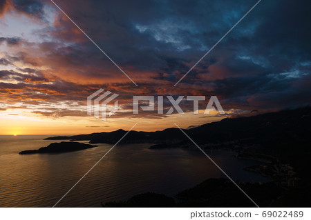 Fiery red and blue sky during sunset over the Budva Riviera in Montenegro and the island of St. Nicholas. 69022489