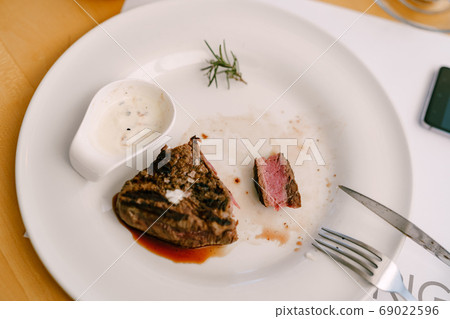 A cut piece of steak with blood on a plate. A cut piece of steak with blood on a plate. 69022596
