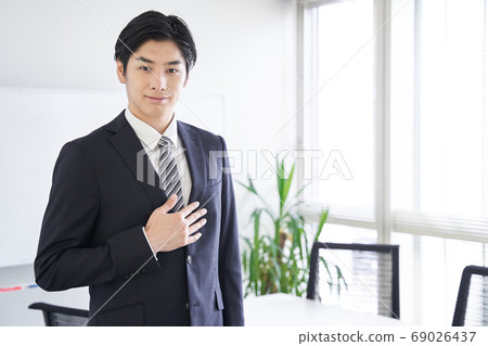 日本男性商人將他的手放在他的胸部在會議室 69026437