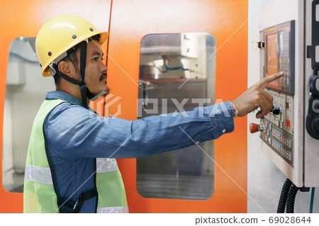 side view of man engineer  working on machine control panel display 69028644