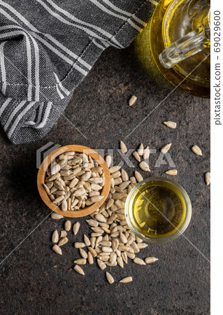 Peeled sunflower seeds in wooden bowl and oil. Peeled sunflower seeds in wooden bowl and oil. 69029600