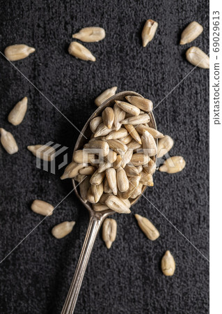 Peeled sunflower seeds in silver spoon. 69029613
