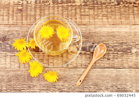 Glass cup of green tea with flowers of calendula on wooden background 69032445