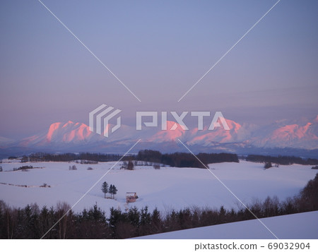 A house with a red roof and the Daisetsuzan system in the evening glow 69032904