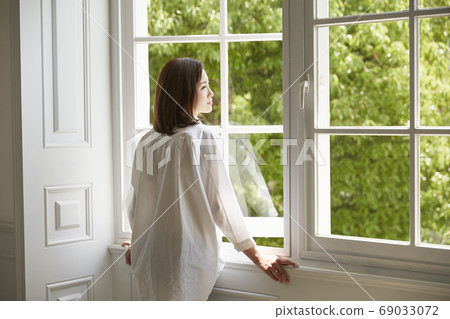 young asian woman staying at home looking out of 69033072