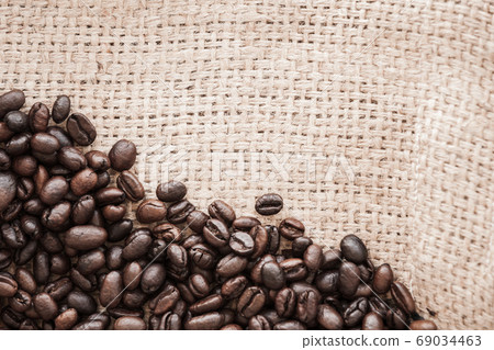 Roasted coffee beans lay over jute bag fabric. Flat lay 69034463