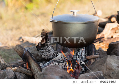 Metal cauldron boiling on a bonfire. Cooking on open fire Metal cauldron boiling on a bonfire. Cooking on open fire 69034468