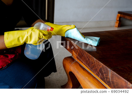 The housekeepers used cloth and cleaning solution to clean the table and chair The housekeepers used cloth and cleaning solution to clean the table and chair 69034492