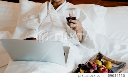 Picture of tourists used laptop and eating fruits on the bed, health food concept Picture of tourists used laptop and eating fruits on the bed, health food concept 69034530