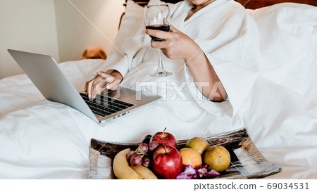 Picture of tourists used laptop and eating fruits on the bed, health food concept Picture of tourists used laptop and eating fruits on the bed, health food concept 69034531