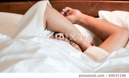 Photo of young woman stretching in bed after wake up Photo of young woman stretching in bed after wake up 69035196