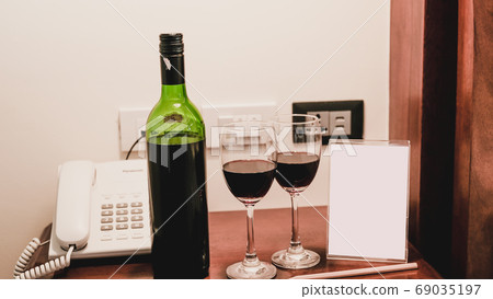 Two glasses of wine and wine bottle with phone on the wooden table Two glasses of wine and wine bottle with phone on the wooden table 69035197