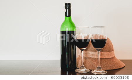 Two glasses of wine and wine bottle with hat on the wooden table Two glasses of wine and wine bottle with hat on the wooden table 69035198