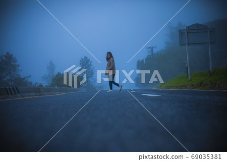 lonely woman on foggy highway lonely woman on foggy highway 69035381