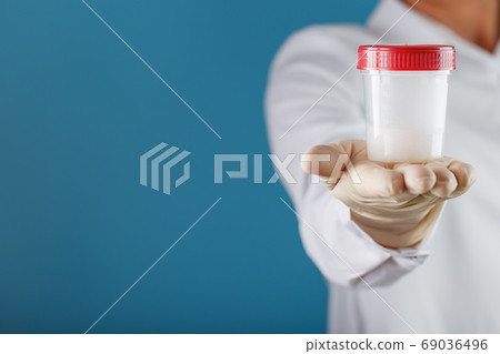 A doctor's gloved hand holding a bottle of a A doctor's gloved hand holding a bottle of a 69036496