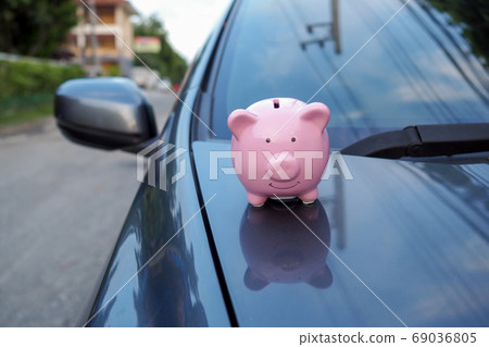 pink piggy bank standing on the black car saving money for new car or saving money with insurance pink piggy bank standing on the black car saving money for new car or saving money with insurance 69036805