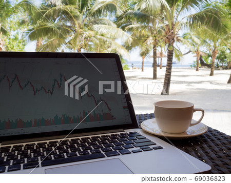 A cup of coffee beside laptop with Coconut tree and sea view, white sand beach background A cup of coffee beside laptop with Coconut tree and sea view, white sand beach background 69036823