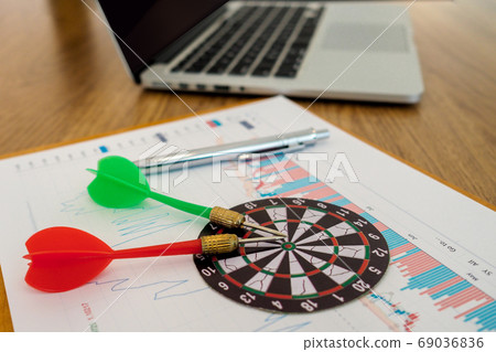 Two darts aiming at the target center of dart board onthe table, Setting challenging trading goals Two darts aiming at the target center of dart board onthe table, Setting challenging trading goals 69036836