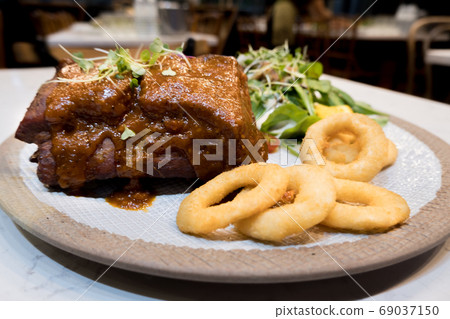 Pork Rib Steak Organic salad vegetables In a white tile dish with fried onions 69037150