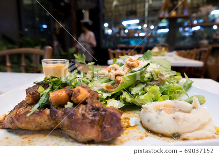 Pork steak, hot dog and organic salad In a white dish with mashed potatoes Pork steak, hot dog and organic salad In a white dish with mashed potatoes 69037152