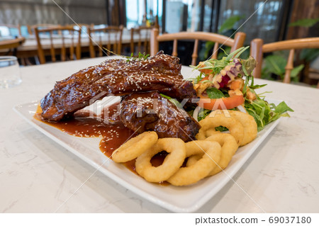 Pork Rib Steak Organic salad and fried onions, served in a white plate 69037180