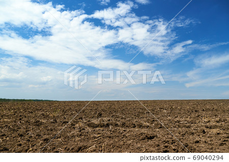 plowed field and blue sky, soil and clouds of a bright sunny day - concept of agriculture 69040294