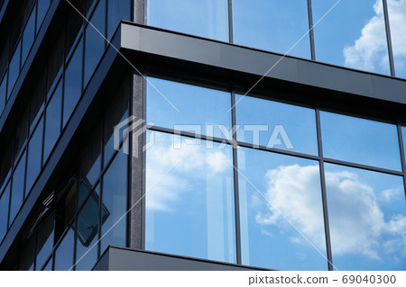 facade of a modern building on a bright Sunny day, blue sky and clouds reflecting in a glass, beautiful exterior of the new building 69040300