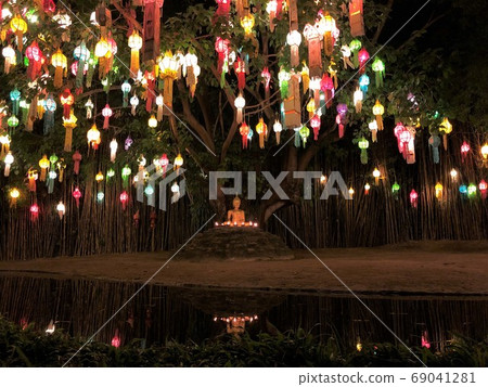 Colorful lamps with a buddha image underneath. Night time. Reflection of the buddha image in the water. Taken at Wat Phan Tao temple, Chiang Mai. Colorful lamps with a buddha image underneath. Night time. Reflection of the buddha image in the water. Taken at Wat Phan Tao temple, Chiang Mai. 69041281