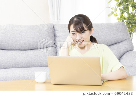 看一台計算機的屏幕的婦女有微笑的 69041488