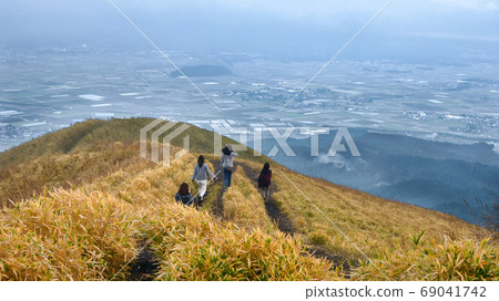 A woman overlooking the Aso city from Daikanbo. Autumn scenery with beautiful Japanese pampas grass. 69041742