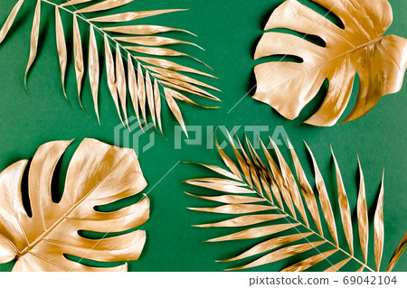 Gold tropical palm leaves Monstera on green background. Flat lay, top view minimal concept. 69042104