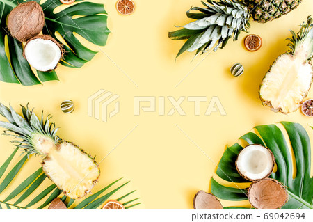 Tropical frame, background with exotic fruits and tropical palm leaves on yellow background. Flat lay, top view Tropical frame, background with exotic fruits and tropical palm leaves on yellow background. Flat lay, top view 69042694