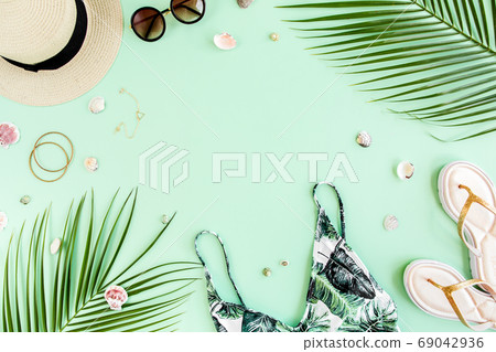 Woman's beach accessories: bikini, rattan bag, straw hat, tropical palm leaves on yellow background. Summer background.  69042936