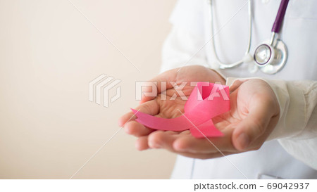 International symbol of Breast Cancer Awareness Month in October. Female doctor hand holding pink ribbon awareness for support people who live w/ breast cancer. Women health care and medical concept. 69042937
