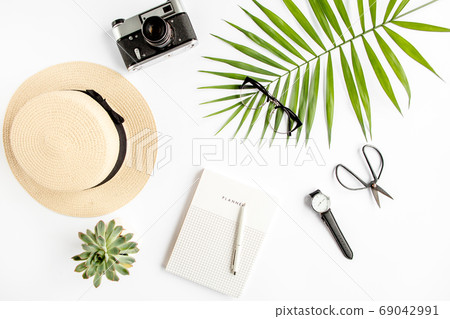 Top view home office desk. Workspace with straw hat, glasses, retro camera, notepad and tropical palm leaf on white background. Flat lay, top view. Top view home office desk. Workspace with straw hat, glasses, retro camera, notepad and tropical palm leaf on white background. Flat lay, top view. 69042991