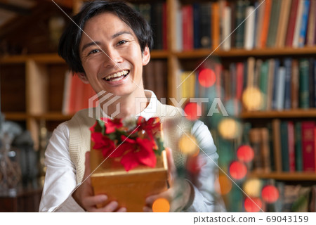 Christmas young man trying to give her a present Christmas young man trying to give her a present 69043159