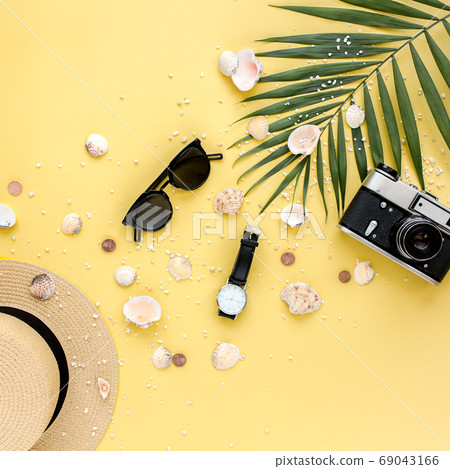 Traveler accessories on yellow background with palm leaf, camera and sunglasses. Flat lay, top view. Summer background. 69043166
