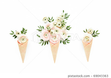 Waffle cone with ranunculus flower bouquet on white background. Flat lay, top view floral background. Waffle cone with ranunculus flower bouquet on white background. Flat lay, top view floral background. 69043363