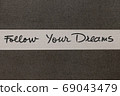 White and Grey coloured paper background with Follow Your Dreams motivational handwritten message 69043479