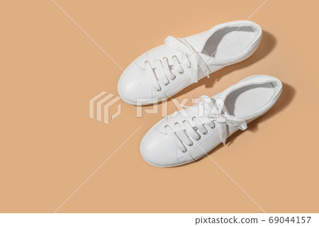 White female gumshoes on beige background. 69044157