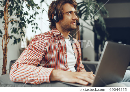 Young man wearing headset doing a video call by laptop 69044355