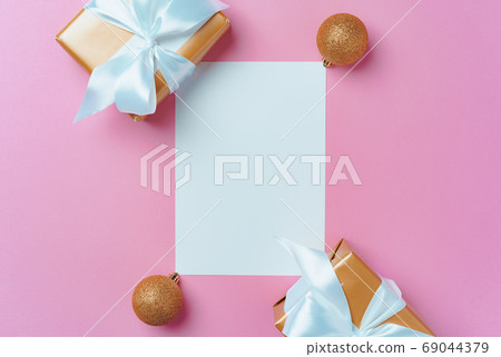 Christmas festive mock up with blank page, wrapped gifts and baubles on pink 69044379