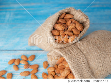 Almond in cloth bag on blurred wooden background Almond in cloth bag on blurred wooden background 69044484