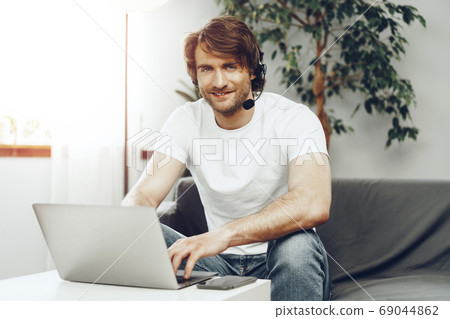 Young man businessman with headset working on laptop from home 69044862