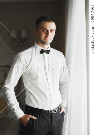 Grooms morning preparation. Handsome man getting dressed and preparing for the wedding 69047462