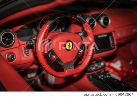 Ferrari F12 Berlinetta V12 GT sports car red dashboard interior shot showing the driving wheel in focus Ferrari F12 Berlinetta V12 GT sports car red dashboard interior shot showing the driving wheel in focus 69048804