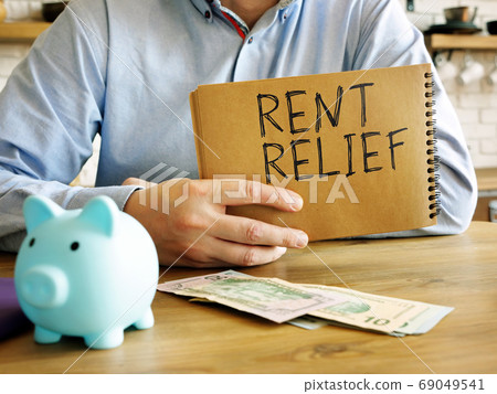 Rent relief. A man at home holds a handwritten lettering. 69049541