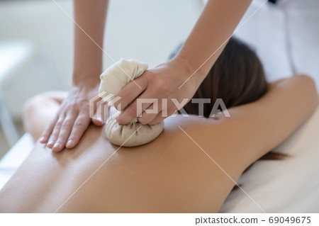 Dark-haired woman having bags ayurvedic massage in salon Dark-haired woman having bags ayurvedic massage in salon 69049675