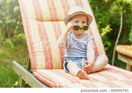 Smiling little baby boy is sitting on the deck chair. 69049791