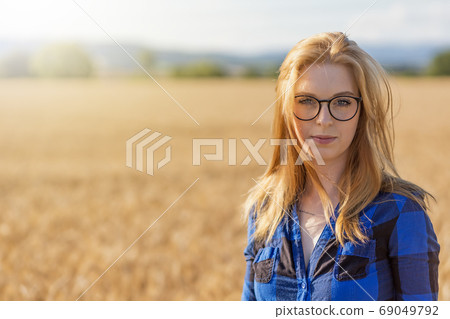 Young woman is posing in corn field looking at the camera. 69049792